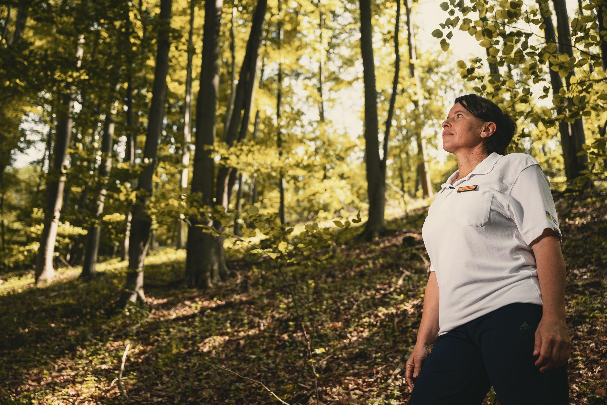 Eine Frau genießt die Ruhe und Stille im Wald.