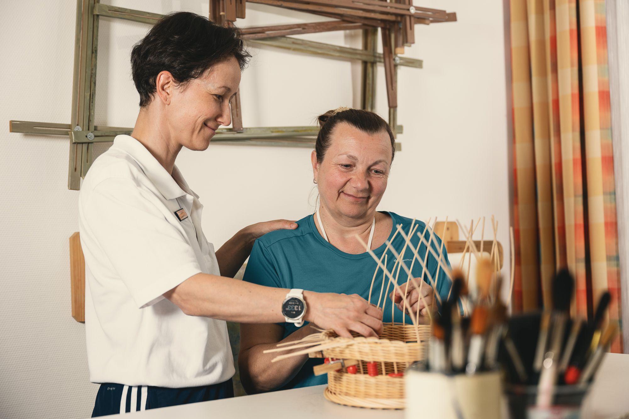 Eine Patienten bei der Ergotherapie flechtet unter Anleitung einer Ergotherapeutin.einen Korb  