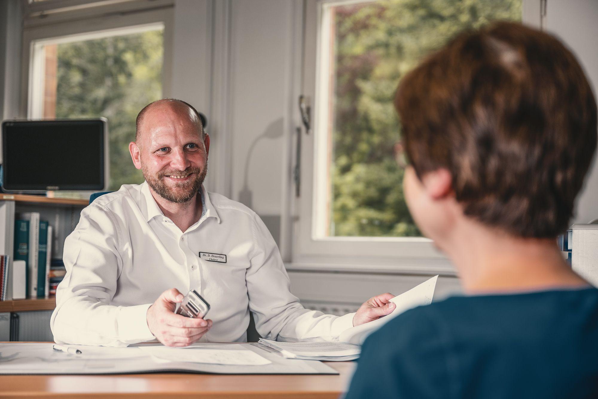 Patientin im Gespräch mit dem Chefarzt in einem Büro.