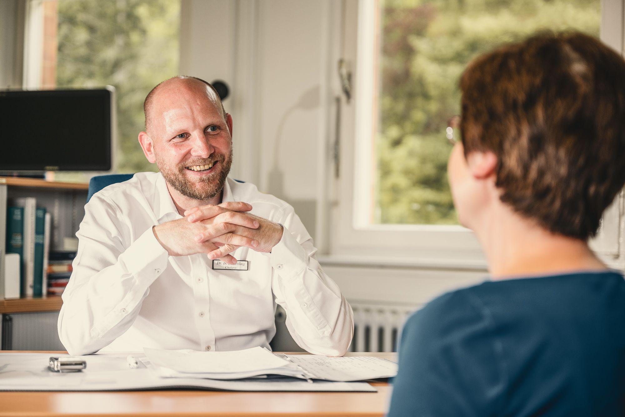 Patientin im Gespräch mit dem Chefarzt in einem Büro.