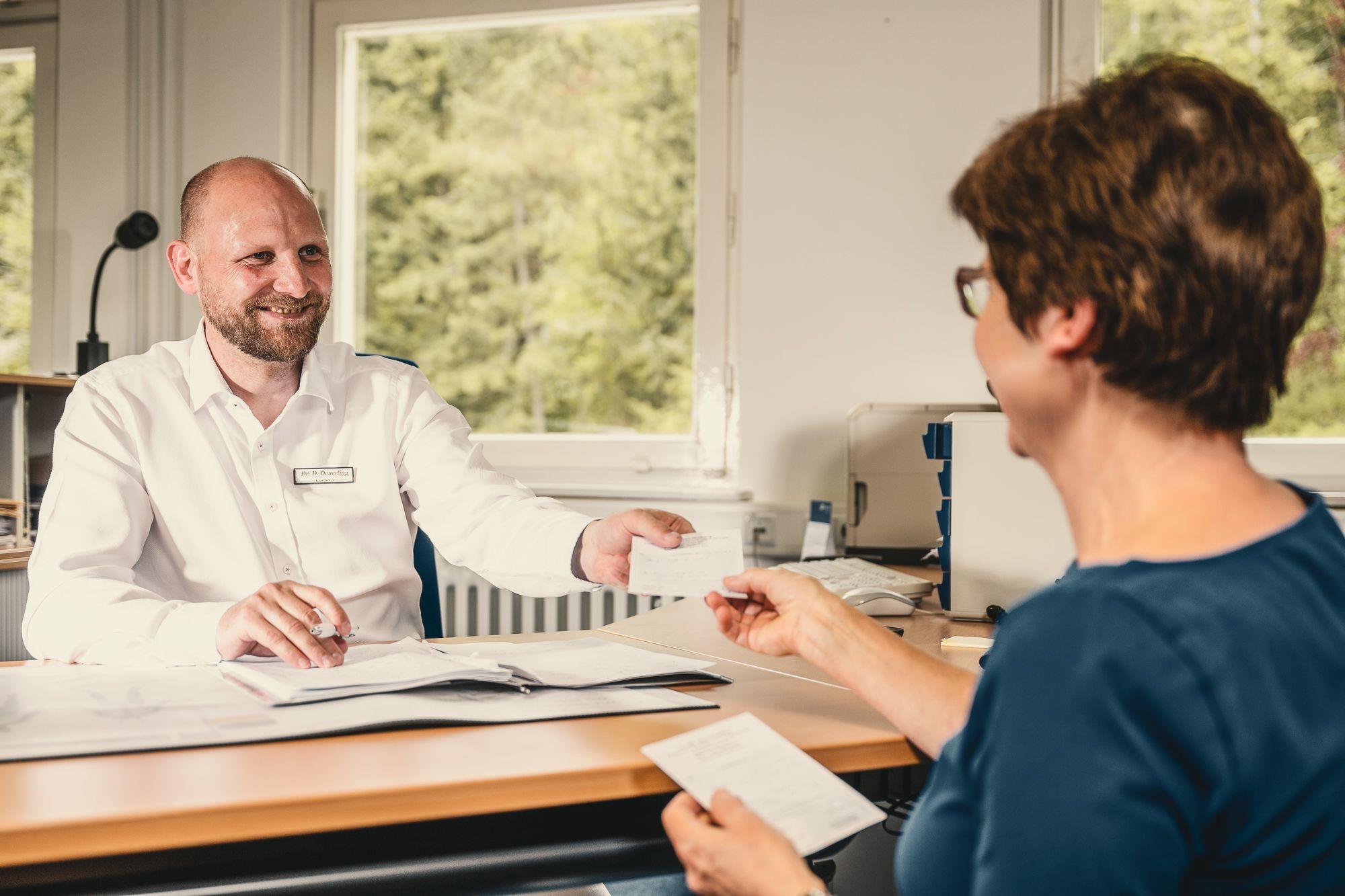 Patientin im Gespräch mit dem Chefarzt in einem Büro.