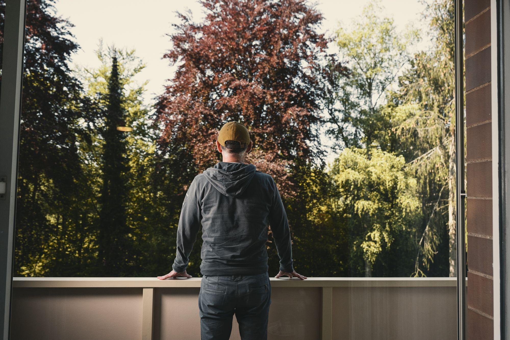 Patient genießt den Ausblick vom Balkon aus in den Wald.