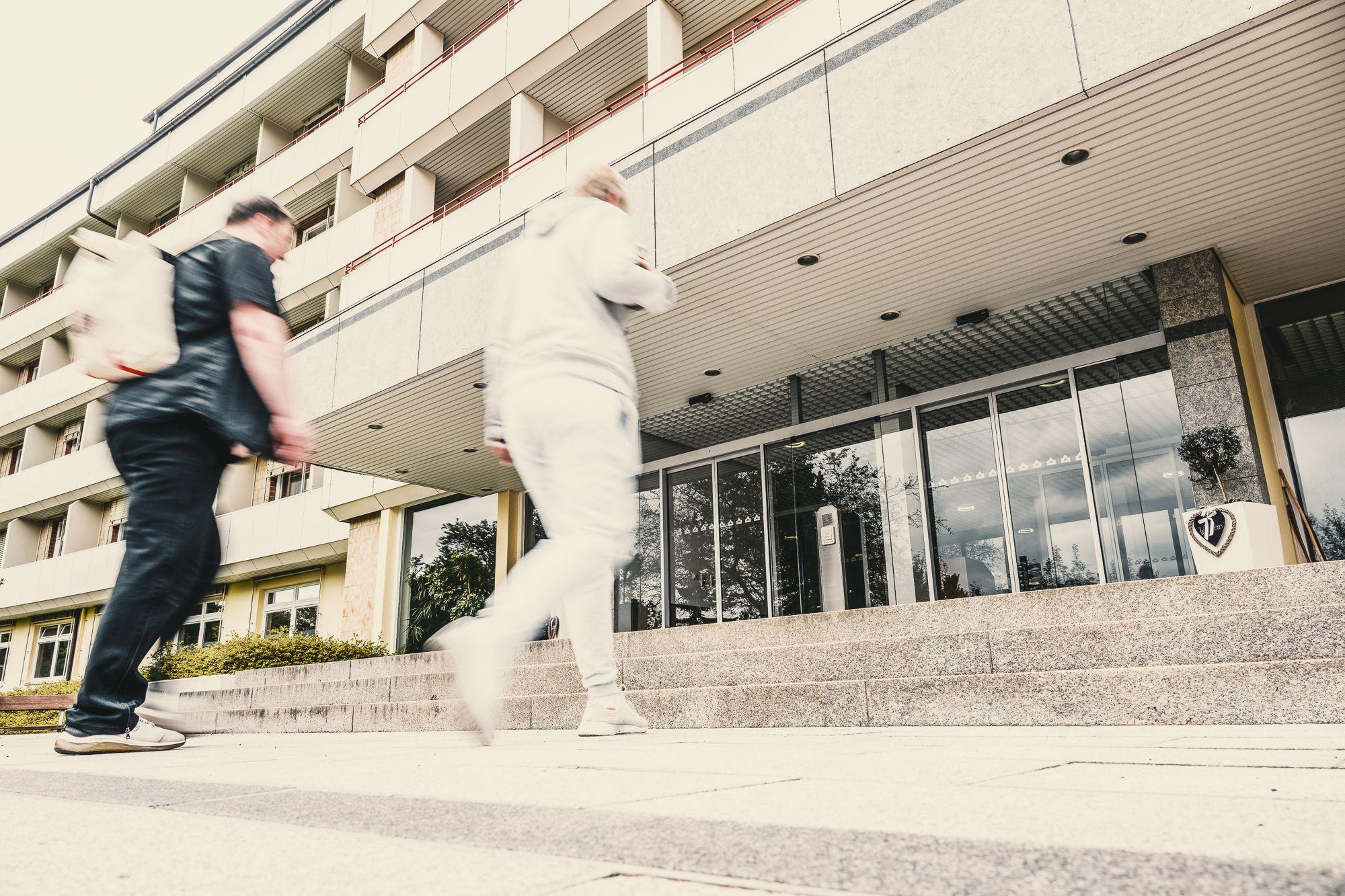 Außenansicht der Rehaklinik Lautergrund. 2 Männer gehen die Treppe zum Eingang hoch. 