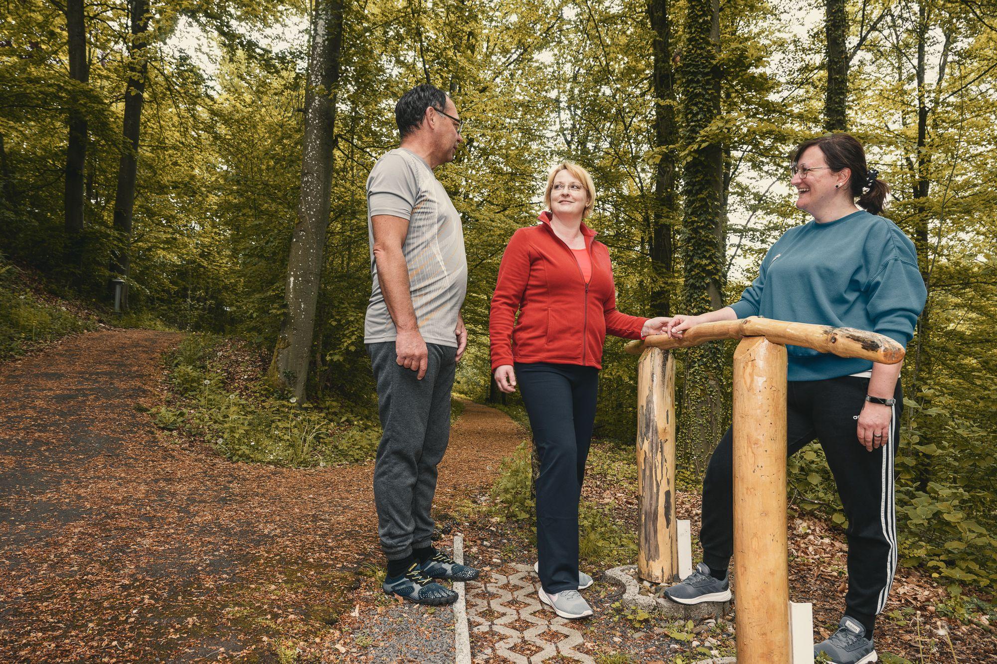 Ein Mann und zwei Frauen stehen an einer Station des Outdoor-Trimmdich-Pfades.