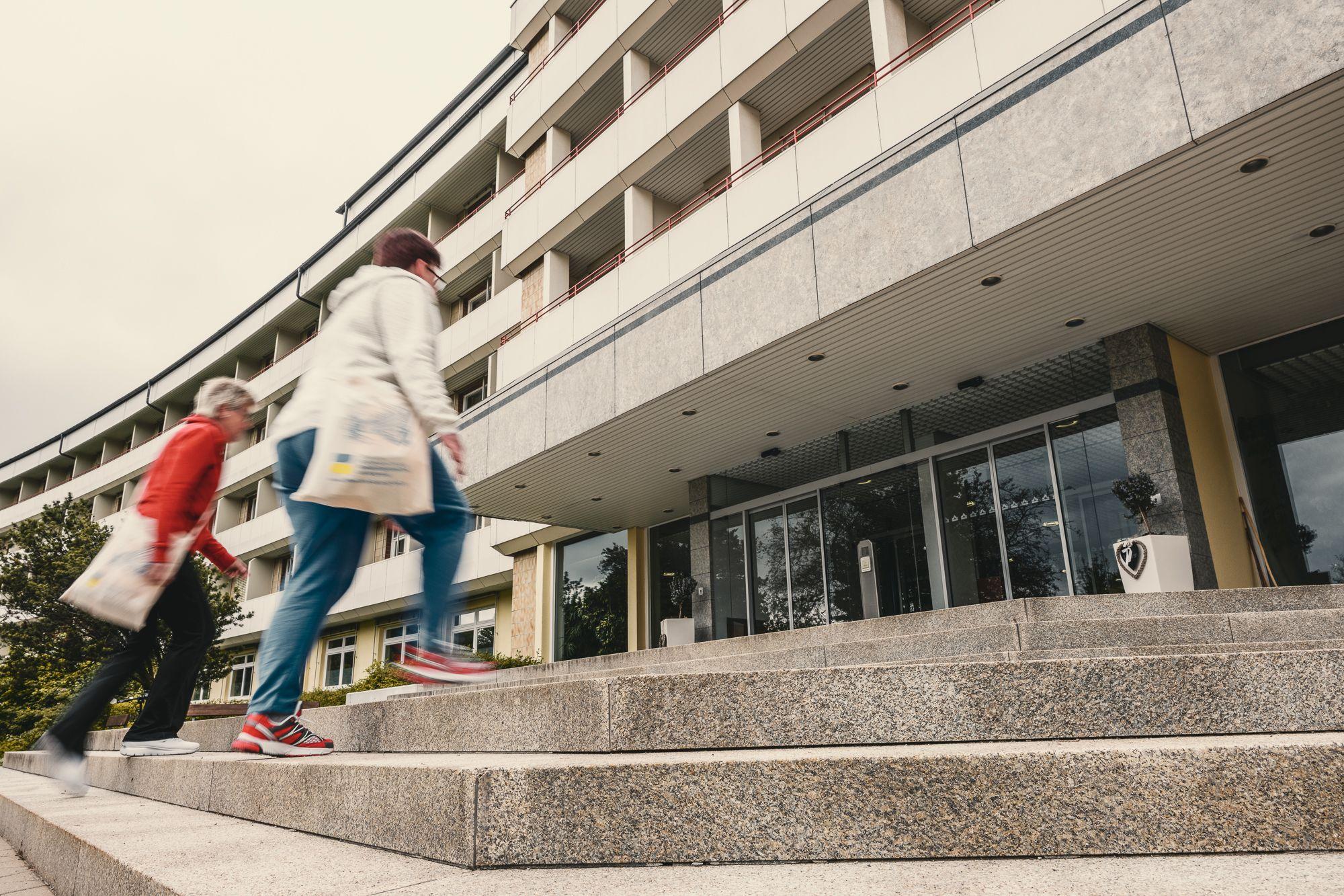 Außenansicht der Rehaklinik Lautergrund. 2 Frauen gehen die Treppe zum Eingang hoch.